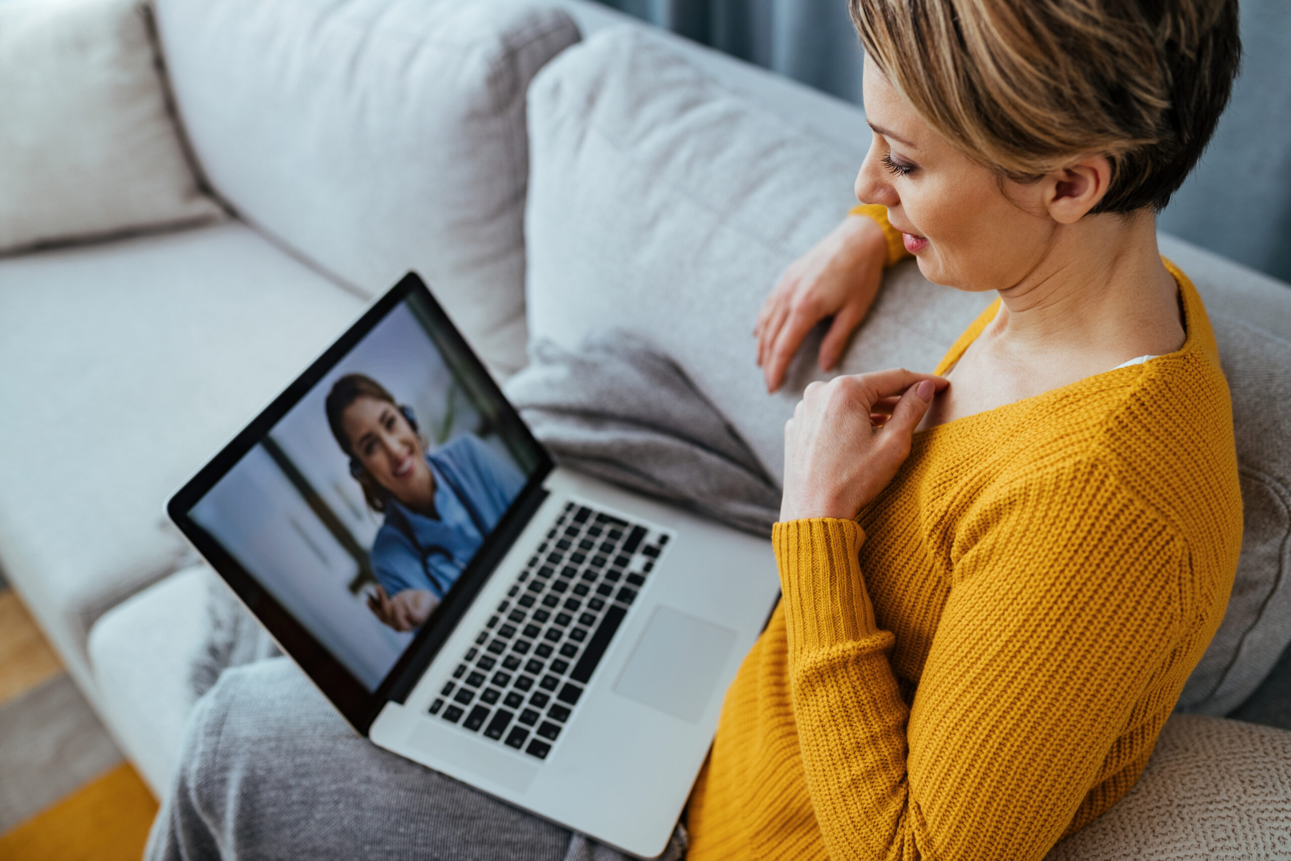 Woman using laptop and having video call with her doctor while s Woman using laptop and having video call with her doctor while s